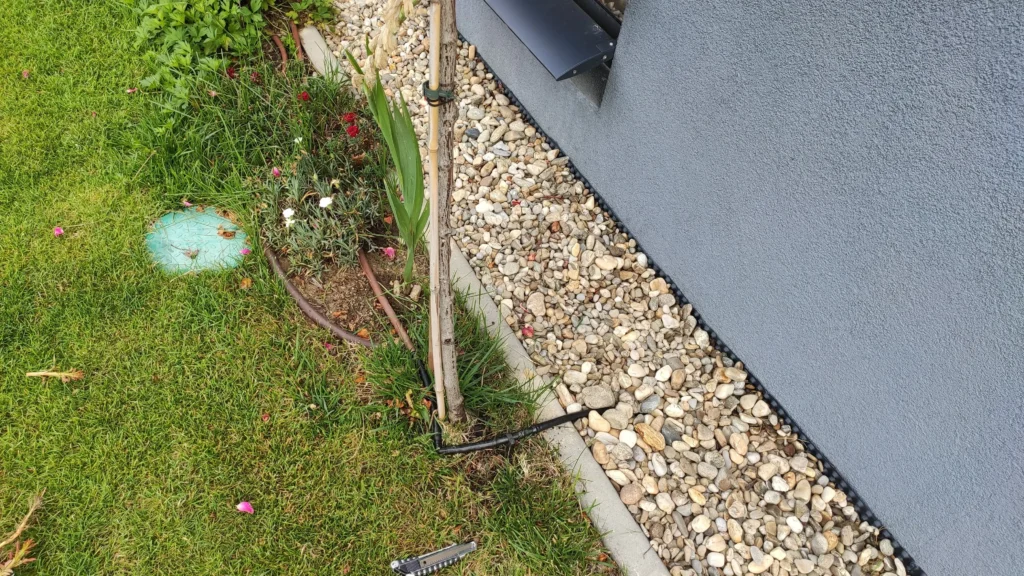 Linie irigații prin picurare instalată lângă peretele casei în zona cu pietriș