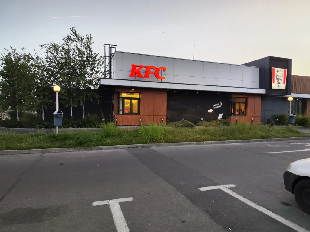 Spațiu verde neglijat cu gazon înalt în fața clădirii KFC