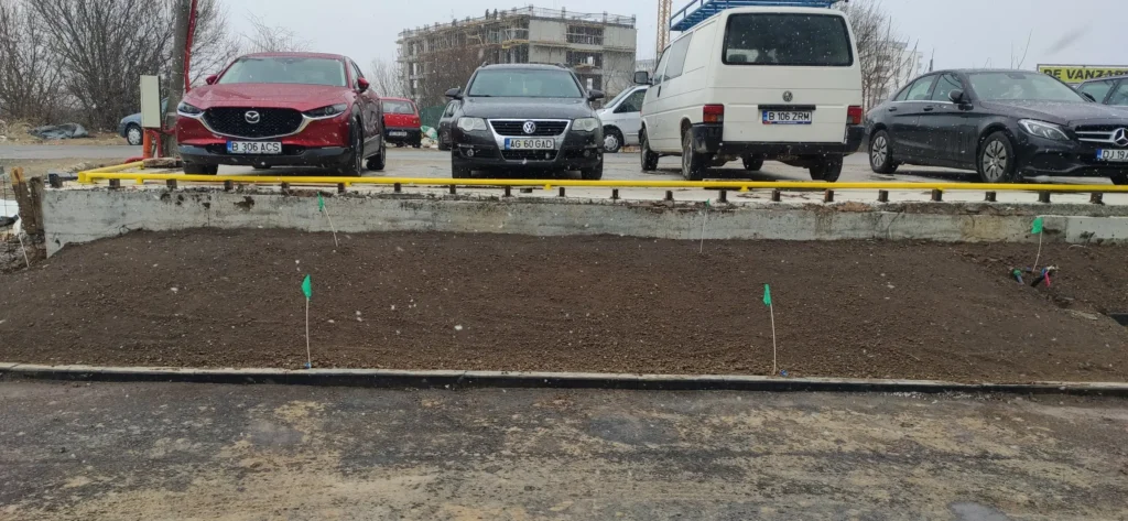 Pregătire teren pentru plantare, cu aspersoare semnalizate lângă parcare , vedere frontală