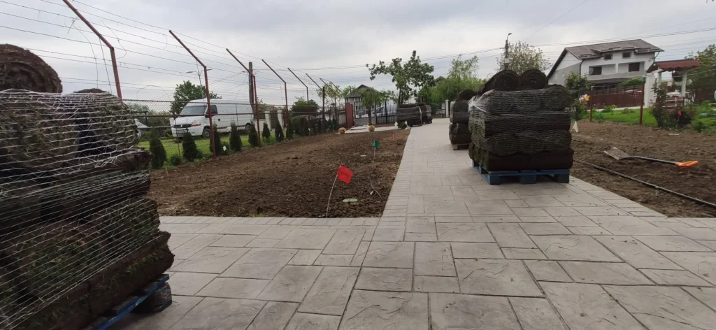 Teren pregătit pentru gazonare și paleți cu gazon rulou pe alee